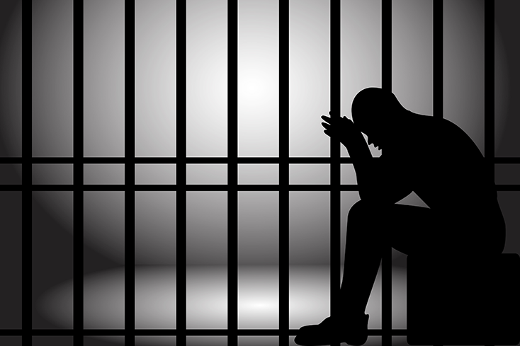 Silhouette of person behind bars