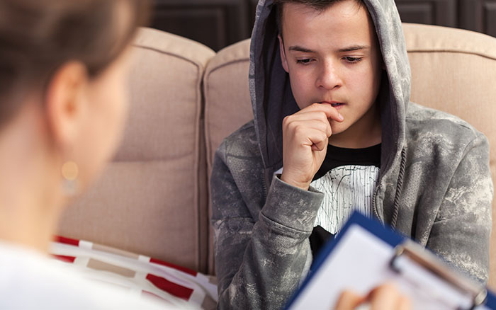 nervous boy biting thumbnail in therapists office