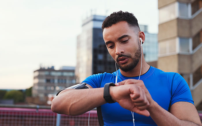 man checking fitness watch while on a jog