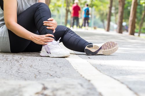 runner sitting on the ground holding their leg