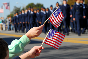 children waving flag as troops march by