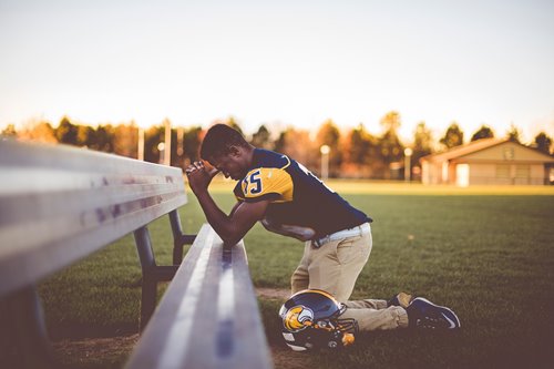 black football player praying