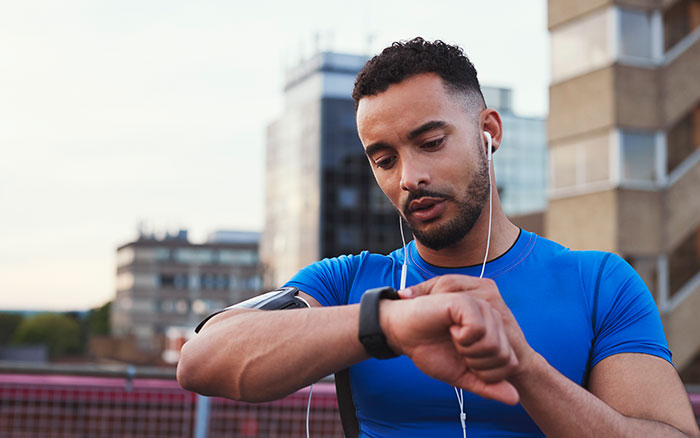 Jogger in athletic clothes looking at his smart watch.