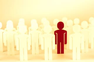 A group of stick figure cutouts with a red stick figure cutout in the middle