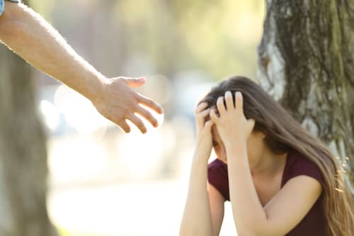 woman sitting by a tree with her head in her hands