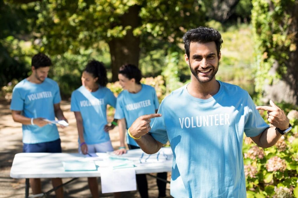 man pointing to the word volunteer on his tee shirt