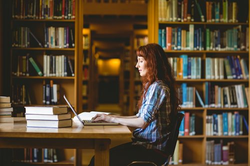 college student doing work at a library