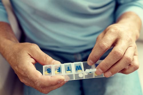 man holding a medication organizer