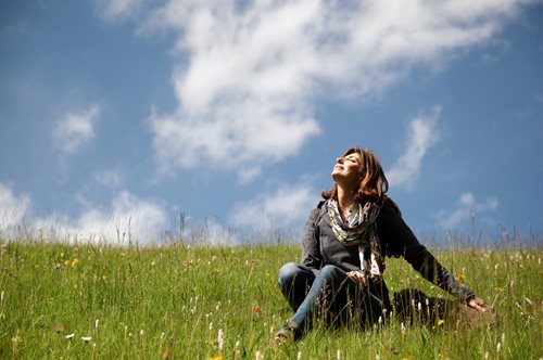 woman sitting in a meadow with sun shining on her face