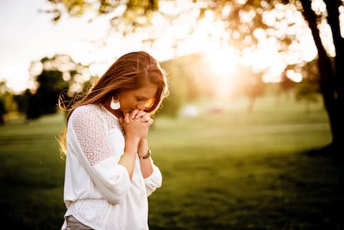 woman walking in the park with her hands folded by her face