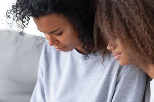 two african american women looking down sadly