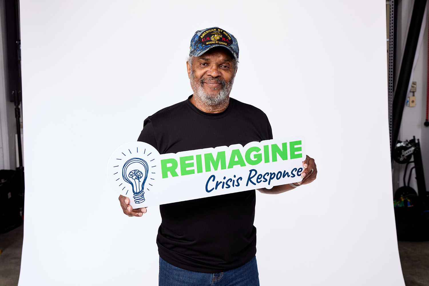 Ray Lay holds sign that reads "Reimagine Crisis Response"