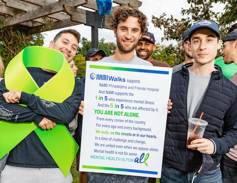 Three young men at a NAMI Walks event holding up event signage