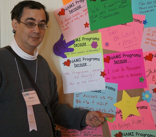 a man pointing to I heart NAMI Programs because... papers hanging on the wall