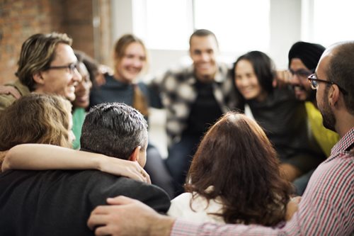 people sitting in a circle arm in arm