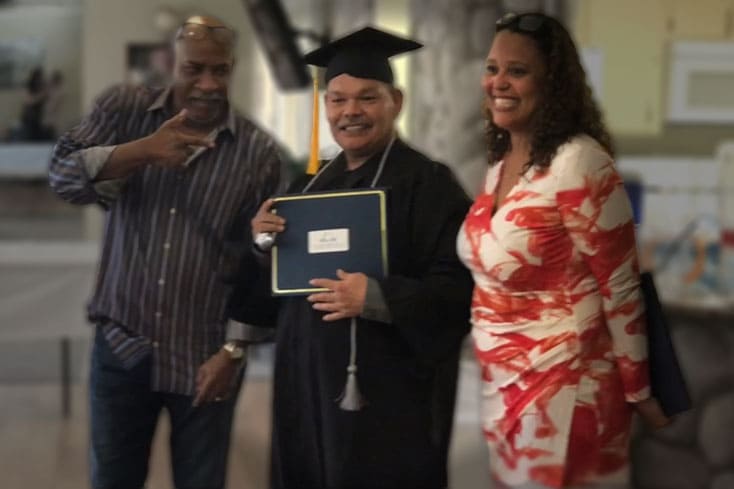 people posing with college graduate