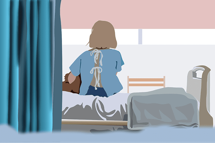 Woman in hospital gown sits on bed
